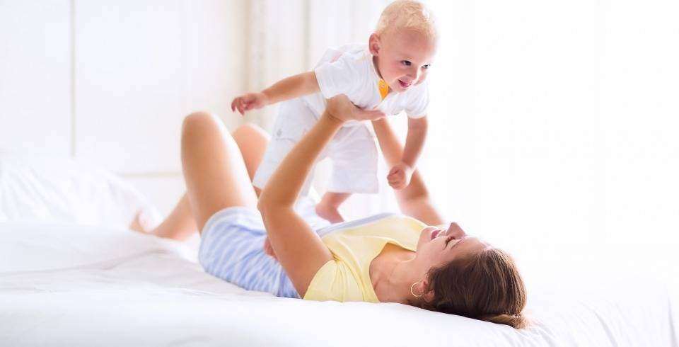Mama in pat se joaca cu bebelusul