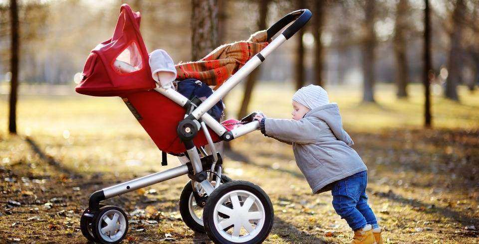 Baiatel se joaca cu caruciorul afara in parc