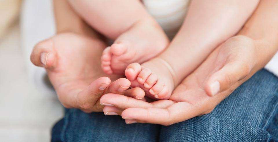 Mama tine picioruse de bebelus in mana